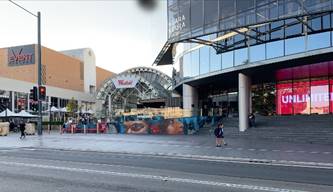 A street with a building and people walking on it

Description automatically generated