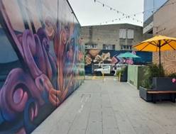A street with a yellow umbrella and a planter

Description automatically generated